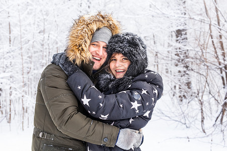 恋爱中的年轻情侣在白雪皑皑的森林里玩得开心。