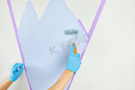 手绘房屋装饰摄影照片_用油漆滚筒和遮蔽胶带手绘墙。