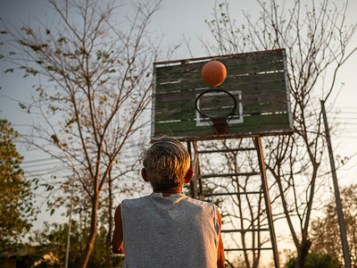 夏日，亚洲老人在操场上打篮球。