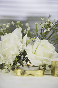 婚礼餐桌装饰，配有假玫瑰和金色蜡烛