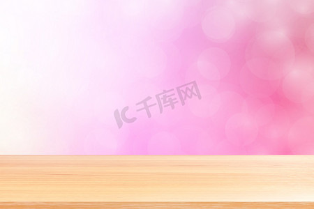 渐变粉红背景摄影照片_空木桌地板在模糊的散景柔和的粉红色渐变背景上，木板空在粉红色散景彩色浅色阴影上，彩色散景灯渐变柔和，用于横幅广告产品