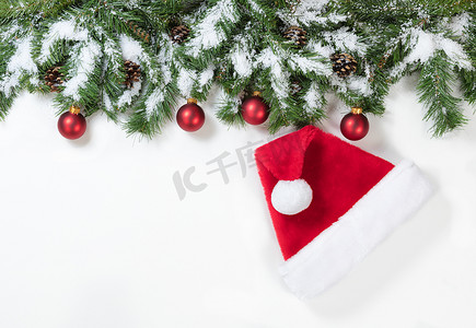 带圣诞老人帽子和红色装饰品的雪圣诞树枝