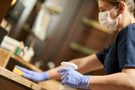 戴防护手套的女服务员对浴室表面进行消毒