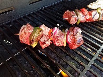 青椒牛肉摄影照片_烧烤架上的木棍上的牛肉和胡椒