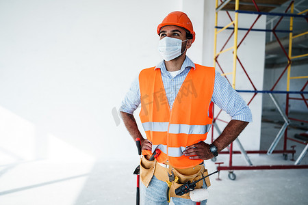 身穿工作服、头戴医用口罩、头戴安全帽的混血男子建筑工人肖像，特写