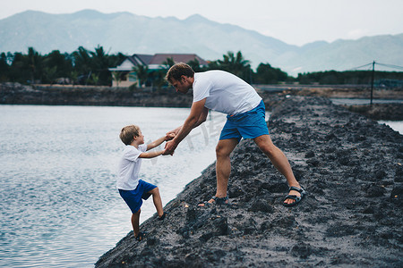 继父摄影照片_爸爸帮助儿子下湖水，解释安全规则。