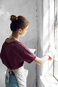 穿白围裙的女人在房屋室内装修中画窗户