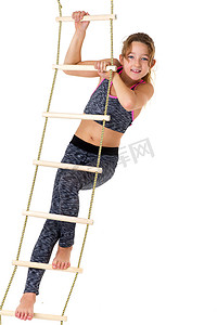 女孩攀岩摄影照片_女孩在绳梯上进行体操锻炼。