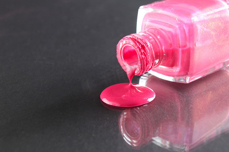 粉色指甲油从黑色背景的瓶子里倒出来，上面有文字的复制空间