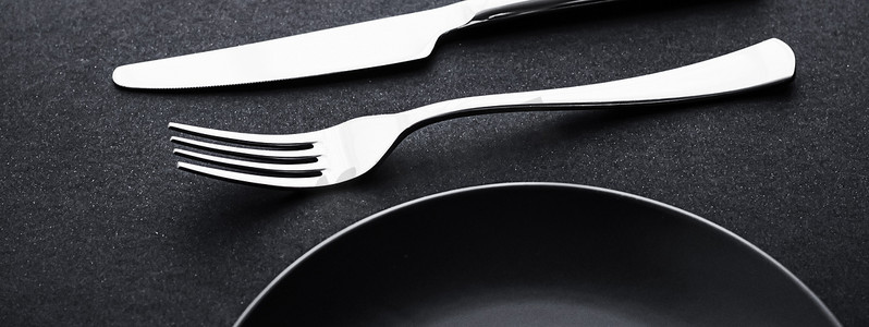 黑色极简摄影照片_黑色背景的空盘子和银器、节日晚餐的优质餐具、简约的设计和饮食