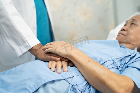 医生手牵着亚洲老年或老年老妇人的手，在护理医院病房里充满爱、关怀、帮助、鼓励和同情，健康强大的医疗理念