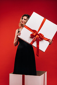 一个穿黑色裙子的女孩站在红色背景的礼盒里