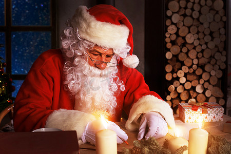 快乐圣诞老人的画像坐在他在家里靠近圣诞树的房间里，并回答圣诞信件。
