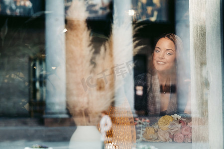 坐在窗边的咖啡馆里，一个留着长发的年轻欧洲女孩的画像，一个穿着长发夹克的高个子女孩，在咖啡馆的窗户反射下