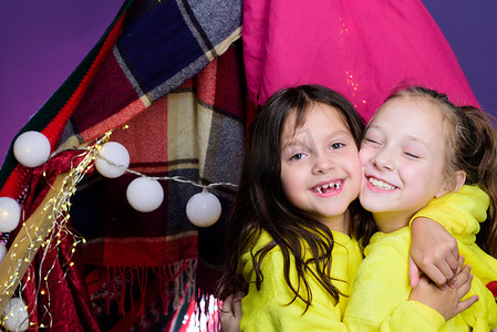 有趣的孩子面对两个可爱的小孩在家里的帐篷里玩耍。