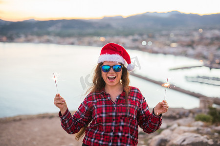 人、美和圣诞节的概念 — 戴着太阳镜和圣诞老人​​帽子的漂亮女人拿着闪闪发光的东西