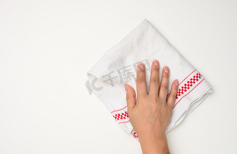 女手拿着白桌上的白色厨房毛巾，顶视图