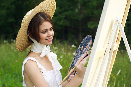 穿着白裙的女人在户外艺术家画架上画画