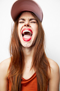 闭着嘴巴摄影照片_戴着帽子、闭着眼睛的女人张开嘴巴，头上的红唇上有情绪