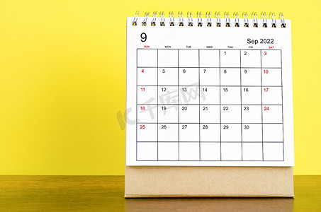 2022 年 9 月的台历，木桌上有黄色背景。