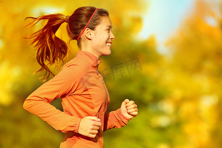越野马拉松摄影照片_跑在秋天秋天森林里的妇女赛跑者