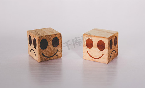 立方体木块上的面部表情与真诚和坦率的情感和表达与桌子上的隐喻，积极与微笑和快乐概念的象征，消极或假与不快乐。