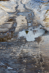 用冰雪覆盖的冬季道路，有水坑和车辙