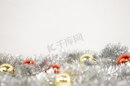 圣诞复制空间，底部有银色装饰链的红色和金色明亮小玩意，白色背景和散景效果