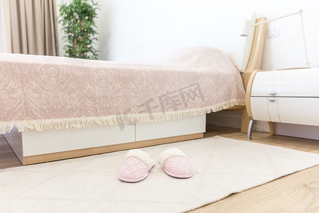 现代风格的卧室，地板上铺着粉色舒适的软拖鞋