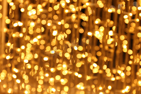 闪光金黄色摄影照片_散景背景和雪形金黄色多彩圣诞快乐，新年快乐散景照明在夜间背景上闪耀，散景闪光，金色豪华背景纹理，闪闪发光的壁纸