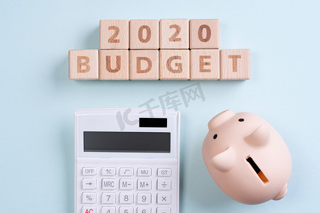 摘要 2020 年财务目标设计概念 — 蓝桌背景上的几何木块立方体，带有存钱罐、顶视图、平躺、复制空间。