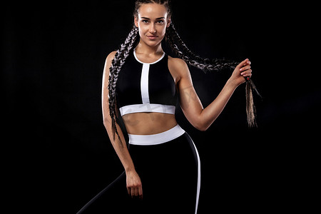 一位穿着黑色运动服、健身和运动动机的黑色背景的强壮运动女性。