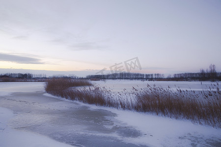 荷兰日落时分美丽的冬季风景，雾雪覆盖着农田和河流，大自然中美丽的色彩