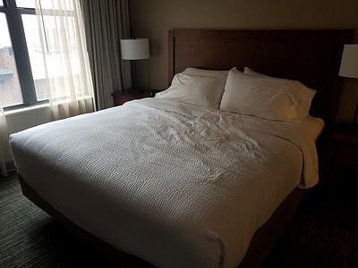 房间里的床铺有白色被子、灯光和窗户