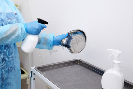 医疗清洁摄影照片_护士在诊所用喷雾器对医疗器械进行消毒。