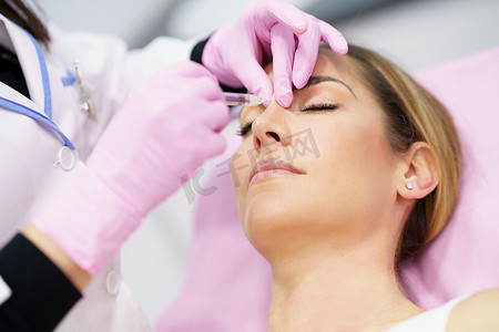 医生通过在病人的鼻子里注射透明质酸来进行隆鼻手术。