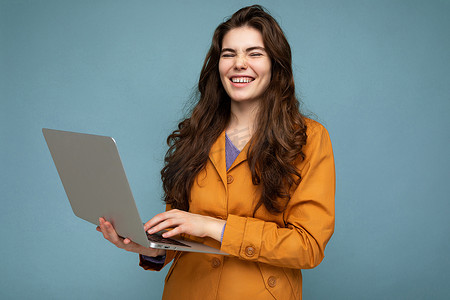 照片中，美丽的年轻女子拿着电脑笔记本电脑，看着彩色背景中突显的相机