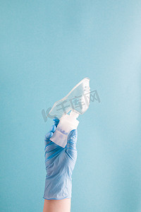 蓝色一次性医用手套中的女性手握有带硅胶面罩的雾化器药物储器、吸入装置、肺病学概念、蓝色背景、复制空间