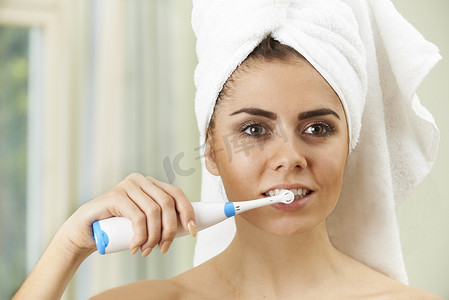 女人在浴室里用电动牙刷刷牙