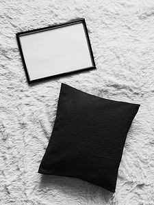 带有空白复制空间的薄木框作为海报照片打印模型、黑色垫枕和蓬松的白色毯子、平躺背景和艺术产品