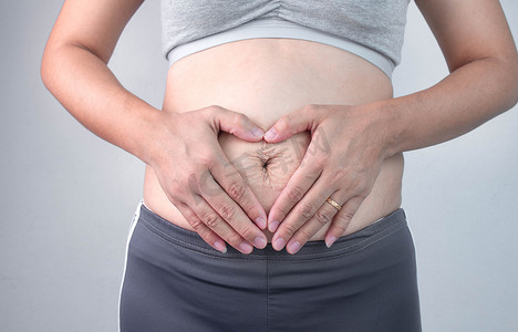 肥胖女性摄影照片_女人触摸腹部皮肤有妊娠纹和厕所的特写