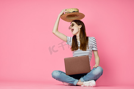 购物娱乐摄影照片_女人坐在地板上，笔记本电脑购物娱乐粉红色背景