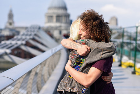 幸福的情侣在伦敦泰晤士河千禧桥旁拥抱。