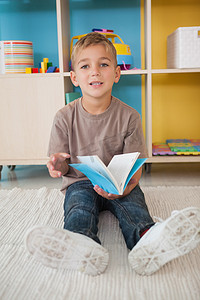 可爱的小男孩坐在地板上在教室里读书