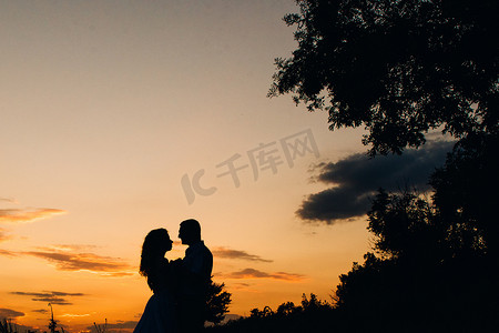 橙色夕阳背景下一对快乐的年轻男女的剪影