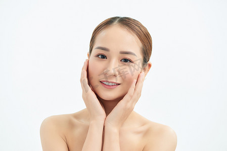 美丽的年轻亚洲女人，双手抚摸着她的脸，皮肤清新干净。
