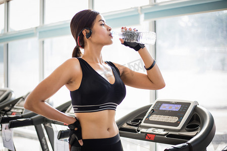 亚洲运动女性在健身房锻炼后喝水。