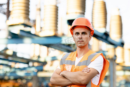 身着制服和头盔的工程师工人站在高塔和配电电缆高压变电站附近的画像