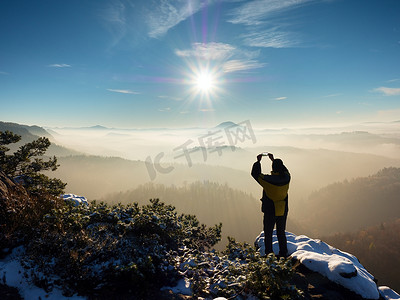 无风摄影照片_徒步旅行者将手机举过头顶，拍摄雾蒙蒙的冬季景观