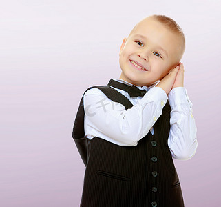 黑色西装白色衬衫摄影照片_穿着黑色西装打领带的时髦小男孩。